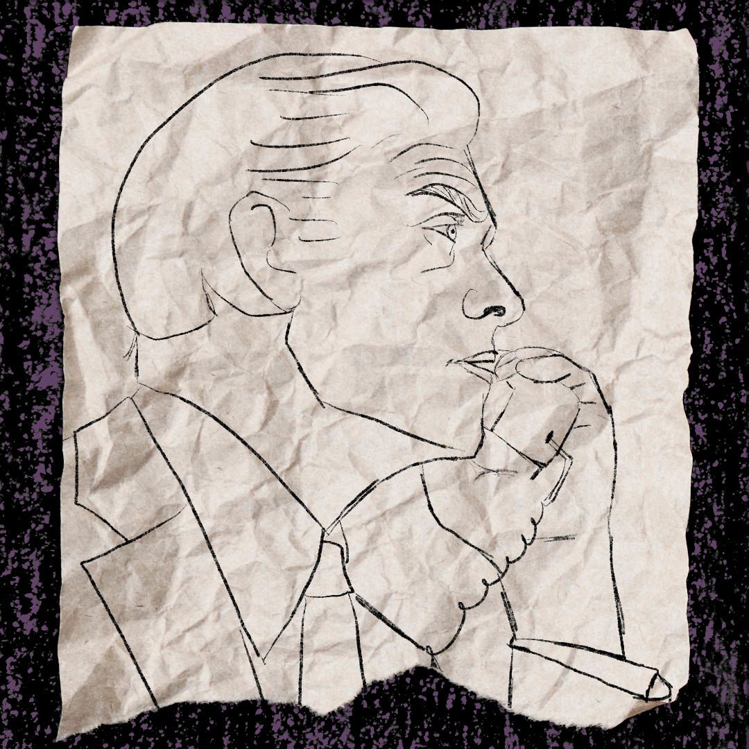 A man in a suit speaking into a landline telephone.